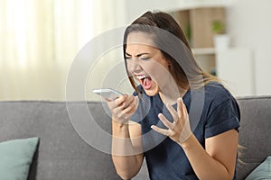 Furious woman shouting to smart phone at home photo