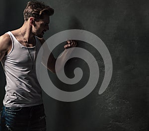 Furious young man punching the concrete wall