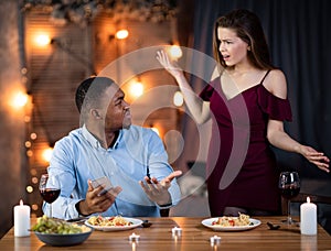 Furious Young Woman Blaming Black Boyfriend For Using Smartphone During Romantic Dinner