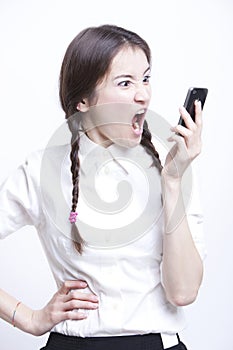 Furious young woman screaming into her cell phone against white background