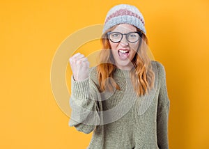 Furious young woman shows fist, isolated on yellow background. Rage pretty girl