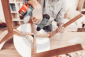 Furniture Assembler with Drill in Hands Repairs Chair.