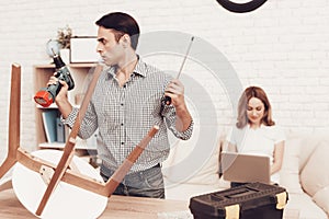 Furniture Assembler Looking Drill in Hand and Girl