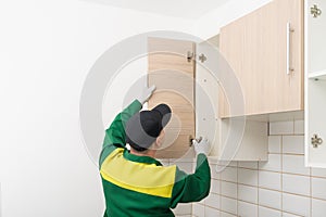 Furniture assembly specialist hangs the fronts on the kitchen cabinet