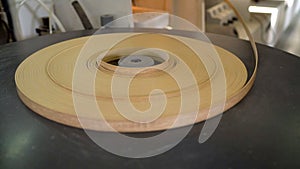 Furniture edge in furniture production. Veneered furniture edge in a roll on the machine.