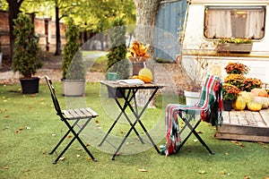 Furniture in fall garden for Picnic or leisure in nature. Leaves in vase, books and cup with tea on table