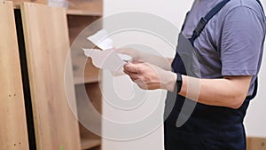 Furniture industry man in professional uniform checking guidance to rack assembling