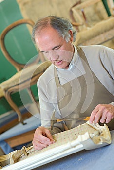 Furniture maker chiselling chair joint in workshop photo