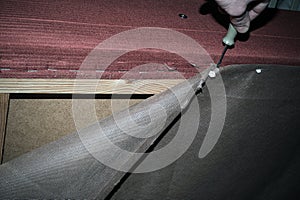 A furniture repair worker replacing the creaking mechanism of an upholstered sofa