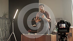 A furniture repairman in a work shop maintains a learning blog on antique furniture repair. General shot of the camera