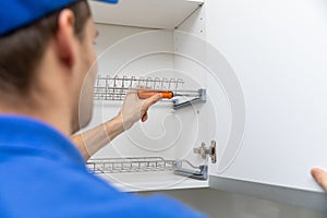 Furniture service worker screwing kitchen cabinet dish rack