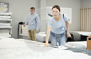 In furniture store, woman examines orthopedic mattress.