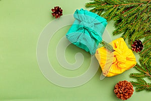 Furoshiki christmas gift and organic christmas decoration on green background. Copy space