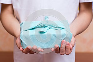 Furoshiki eco-friendly gift wrapped in cloth in children`s hands. Zero waste