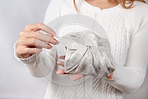 Furoshiki eco-friendly gift wrapped in cloth in woman`s hands