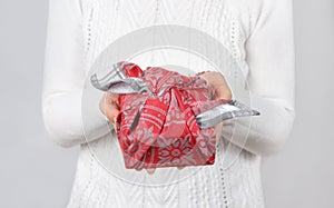 Furoshiki eco-friendly gift wrapped in cloth in woman`s hands