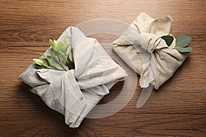 Furoshiki technique. Gift packed in different fabrics decorated with plants on table, flat lay