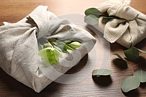 Furoshiki technique. Gift packed in different fabrics decorated with plants on wooden table