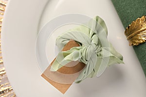 Furoshiki technique. Gift packed in fabric, blank card and napkin on plate, top view