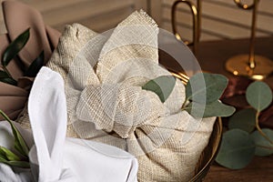 Furoshiki technique. Gifts packed in different fabrics and eucalyptus leaves on table, closeup