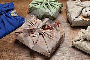 Furoshiki technique. Many gifts packed in fabric and dry leaves on wooden table