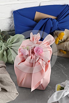 Furoshiki technique. Many gifts packed in fabric on grey table