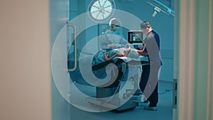 A further away shot of a male and woman surgeon checking up on a patient and making sure her life vitals are okay