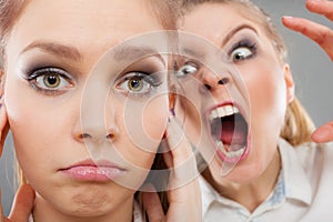 Fury girl screaming at her friend, female closing his ears
