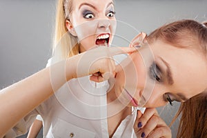 Fury girl screaming at her friend, female closing his ears