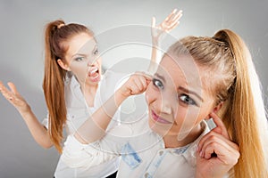 Fury girl screaming at her friend, female closing his ears