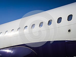 Fuselage of airplane with door and windows. Row of portholes outside the passenger aircraft. Plane on bly sky background