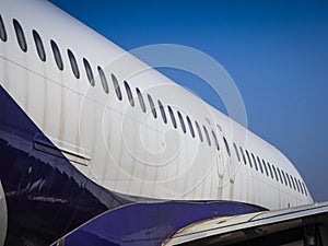 Fuselage of airplane with door and windows. Row of portholes outside the passenger aircraft. Plane on bly sky background