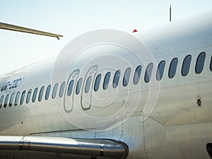 Fuselage of airplane with door and windows. Row of portholes outside the passenger aircraft. Plane on bly sky background