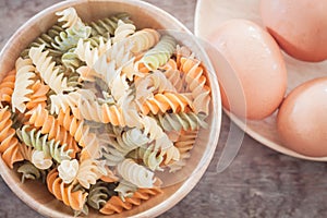 Fusili pasta in wooden plate with eggs