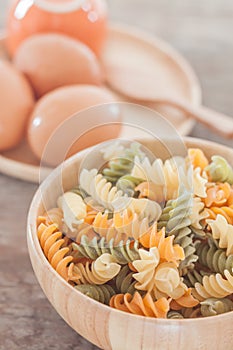 Fusili pasta in wooden plate with eggs