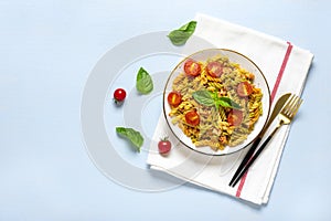 Fusilli - classic italian pasta from durum wheat with chicken meat, tomatoes cherry, basil in tomato sauce in white bowl, napkin,