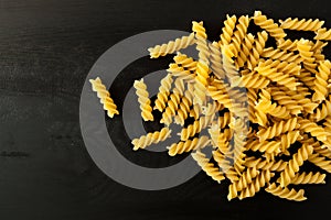 Fusilli italian pasta on a wood black textured background. Close-up view from the top. Free space for text.