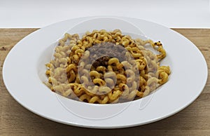 Fusilli Lunghi Bucati with bolognese sauce on a white plate, wooden table. Traditional italian pasta.
