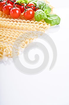 Fusilli lunghi bucati . Long curly pasta on a white plate, with fresh basil leaves and cherry tomatoes. Traditional