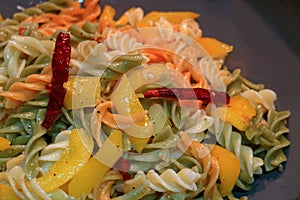 Fusilli pasta with garlic, dried red chili, yellow pepper and olive oil being cooked in a pan