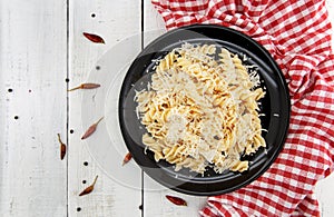 Fusilli pasta with grated parmesan cheese on rustic wooden table