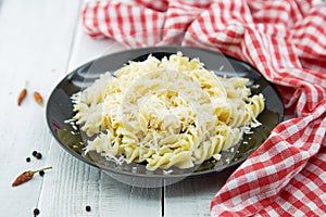 Fusilli pasta with grated parmesan cheese on rustic wooden table