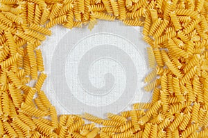 Fusilli pasta making a frame on rustic linen fabric