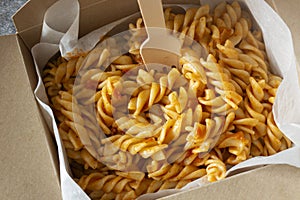 Fusilli pasta in a tomato and herb sauce takeaway in a cardboard box container. Biodegradable eco friendly takeaway