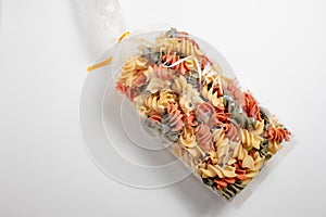 Fusilli type tricolor Italian pasta package closed on a white surface. Concept foods rich in carbohydrates