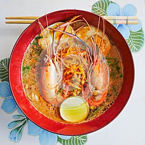 Fusion spicy thai-chinese food in thailand by top view, Tom yum koong-noodle in soup  with topping of shrimps boiled egg parsley