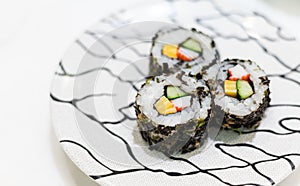 Futomaki, appetizing sushi roll with cucumber, salmon, egg, imitation crab stick and seaweed. Serving on white plate