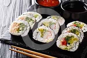 Futomaki rolls with various fillings are served with sauces close-up on a slate board. horizontal