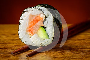 Futomaki sushi roll on chopsticks