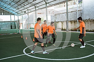 futsal players passing the ball with other players block it